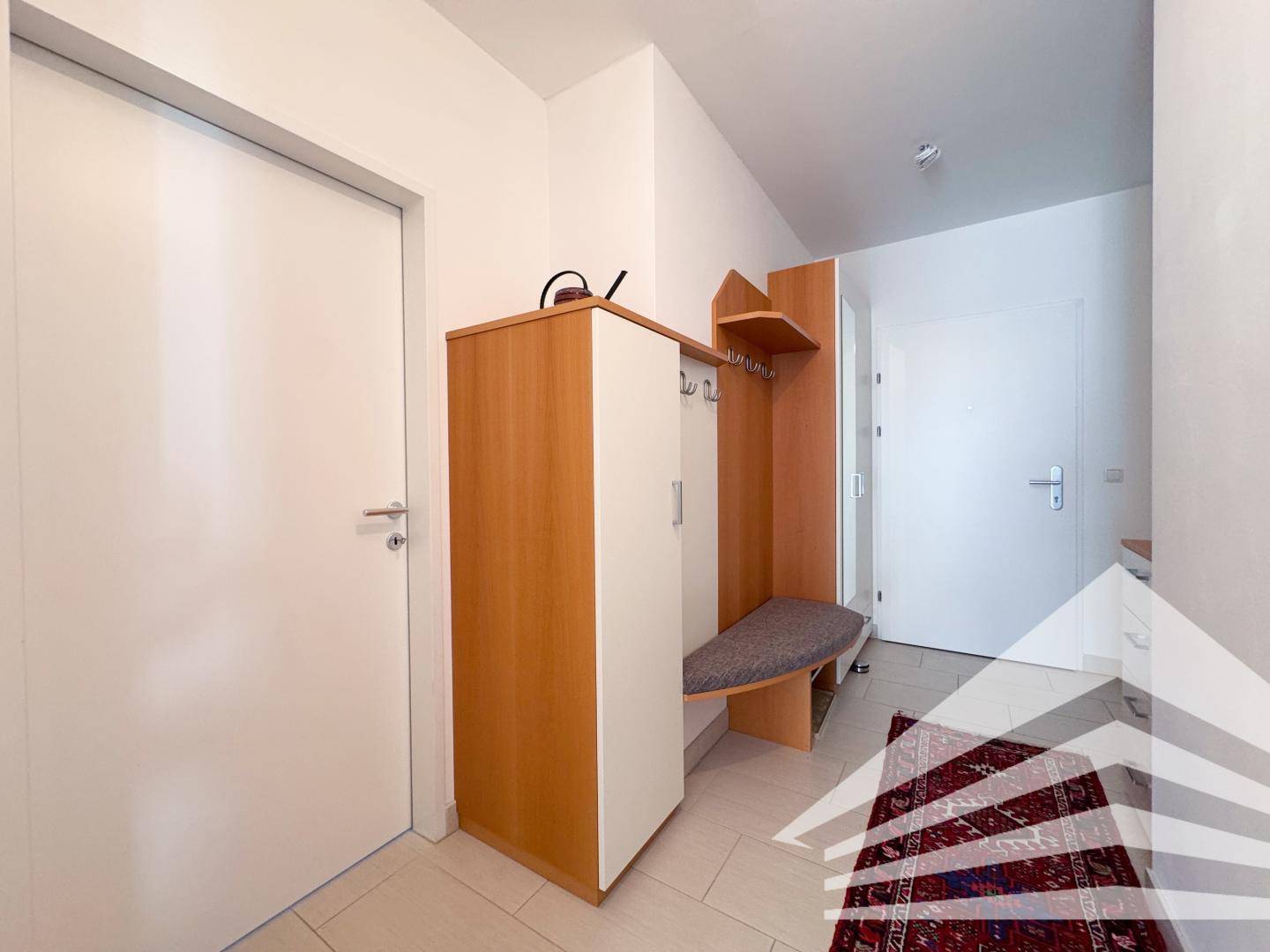 Eingangsbereich mit Garderobe und Schuhschrank, bietet praktischen Stauraum und Zugang zu den Zimmern.