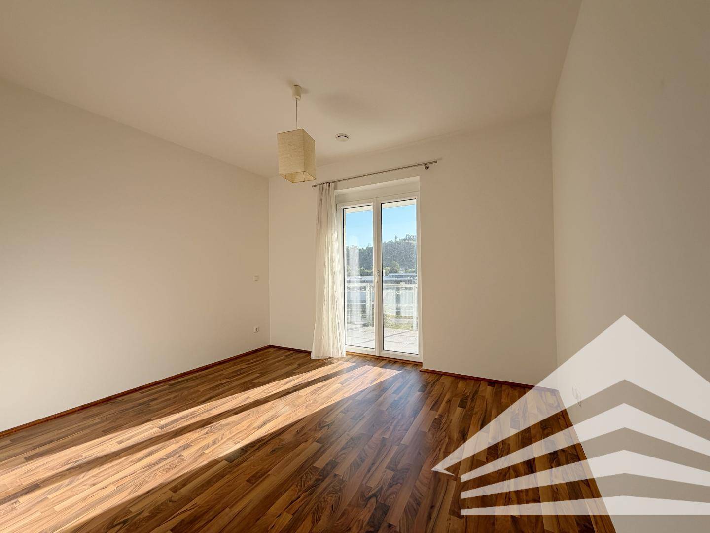 Helles Schlafzimmer mit Parkettboden und Zugang zum Balkon, bietet viel natürliches Licht.