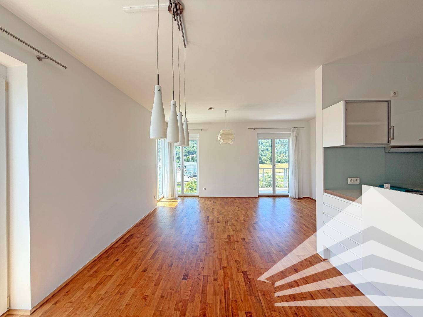 Offener Wohnbereich mit integrierter Küche und Holzboden, bietet helle und moderne Wohnatmosphäre.