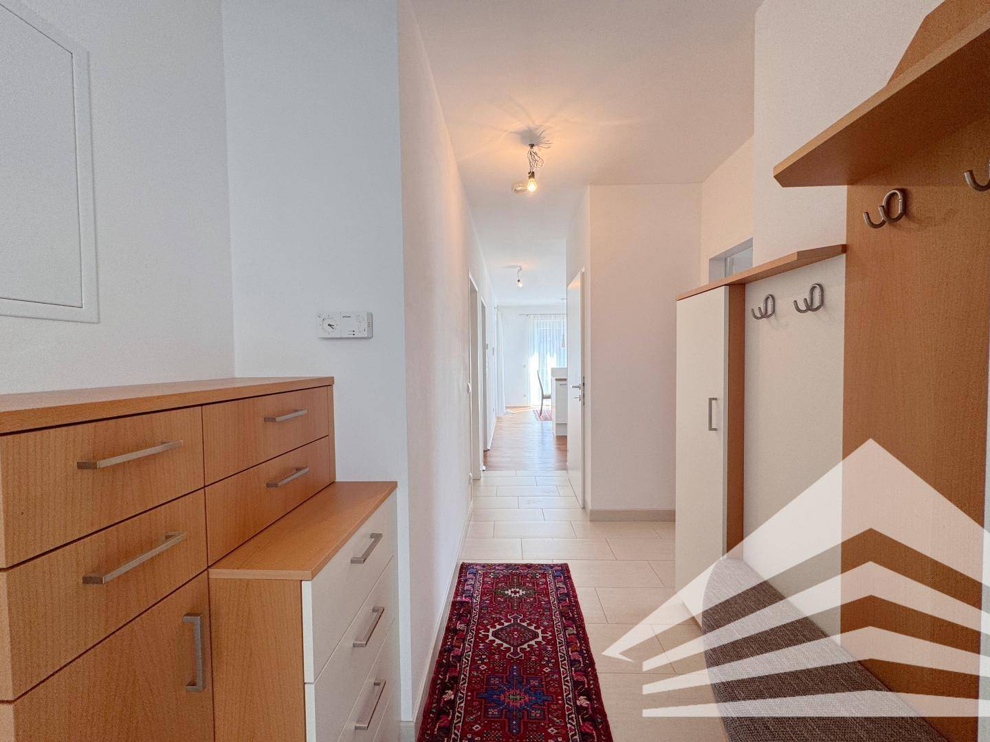 Heller Flur mit Fliesenboden und Garderobe, führt zu weiteren Räumen der Wohnung.