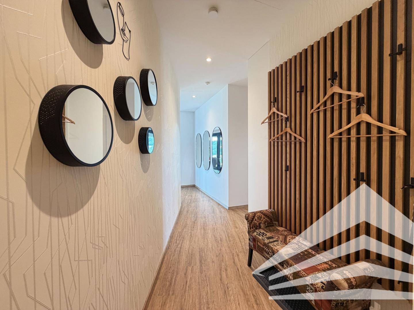 Moderner Flur mit dekorativen Spiegeln und einer Holzlamellenwand mit Garderobe.