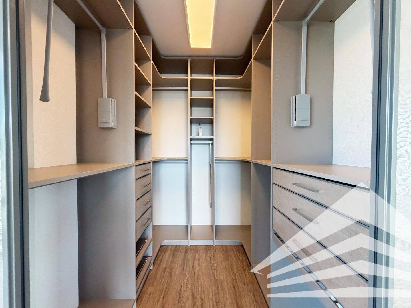 Geräumiger begehbarer Kleiderschrank mit integrierten Regalen und Schubladen für optimale Organisation.