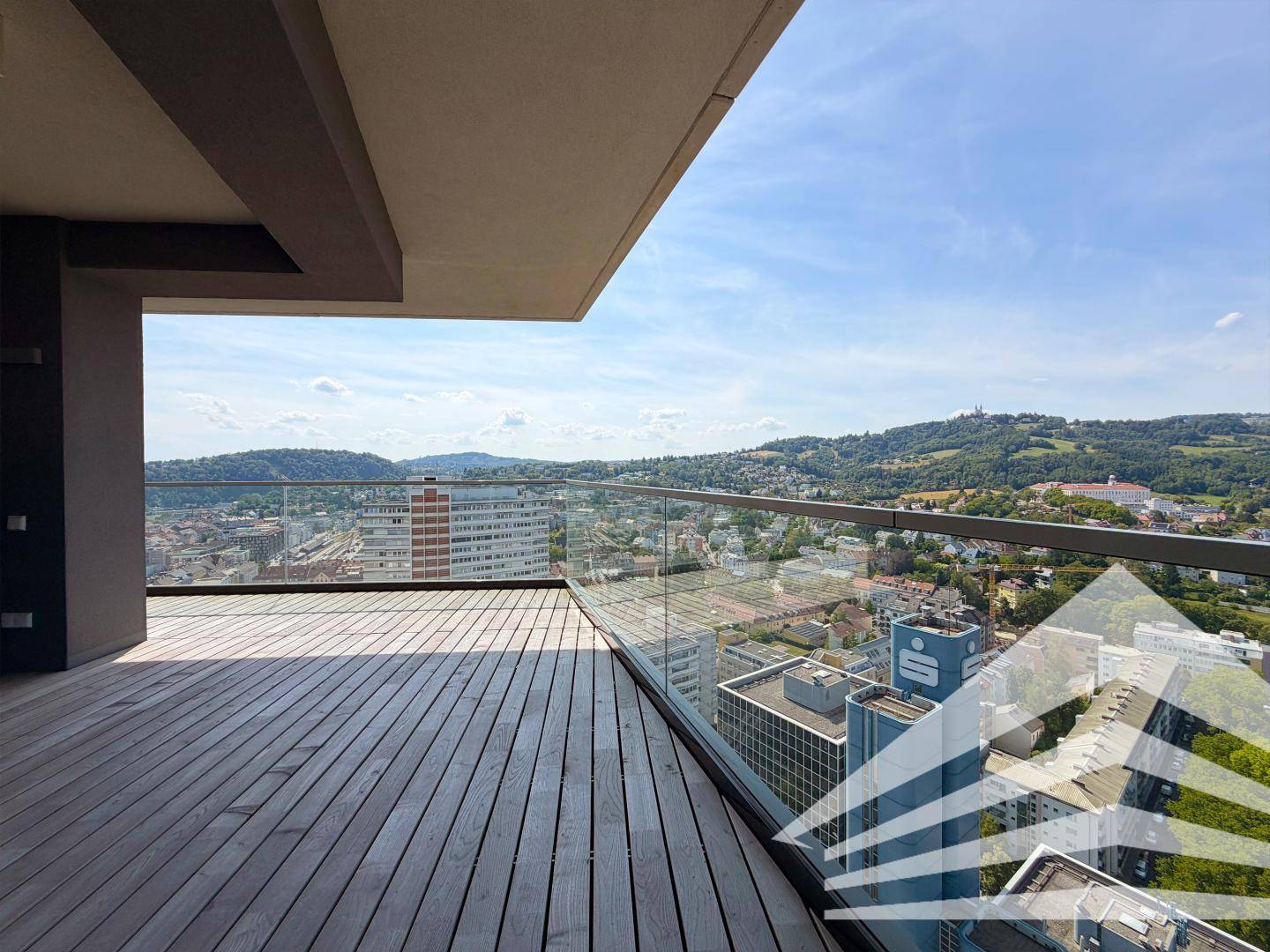 Eckbereich der Terrasse mit Holzboden und Glasbrüstung, ideal für einen weiten Blick über die Stadt.