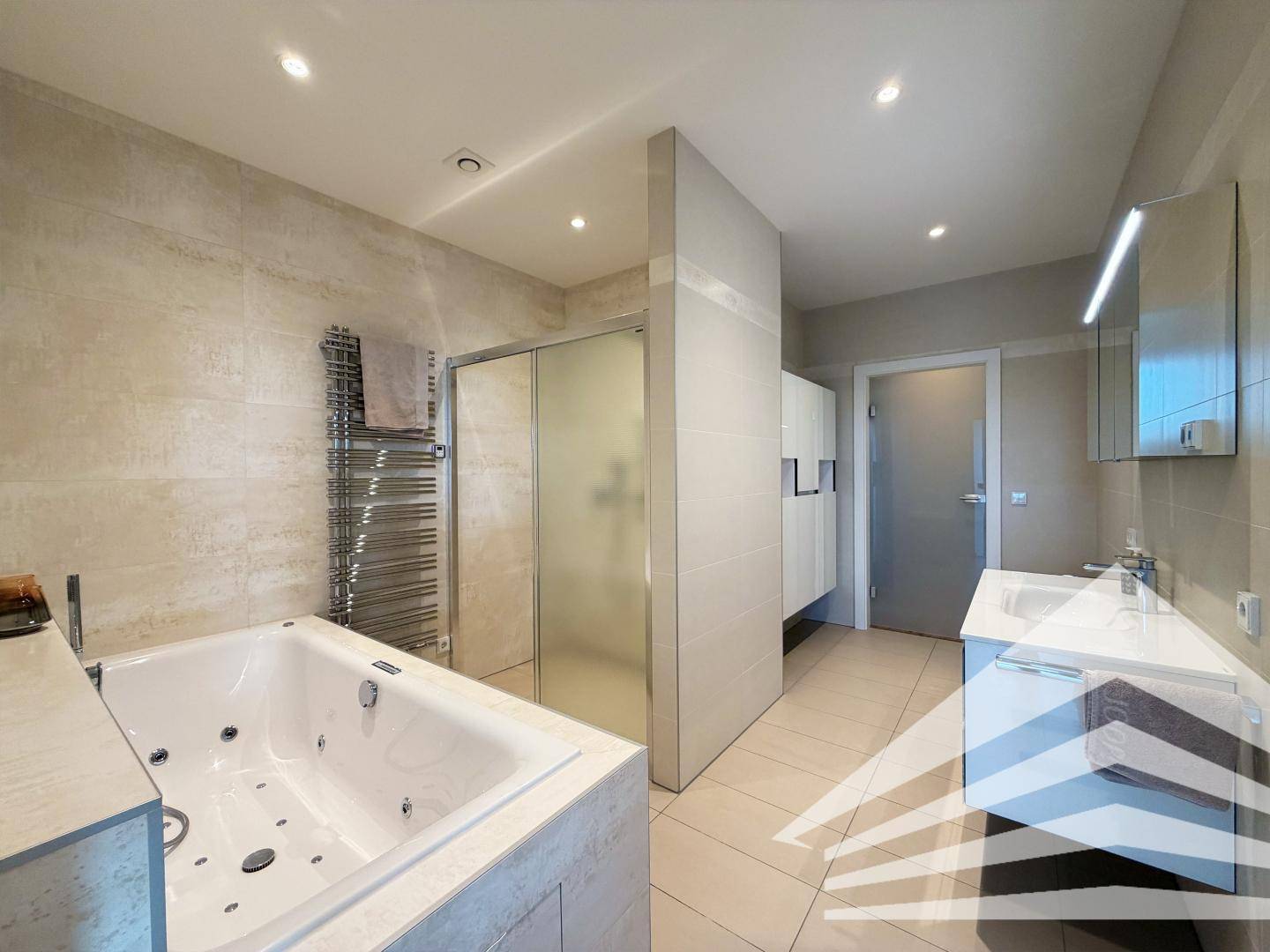 Modernes Badezimmer mit Whirlpool-Badewanne, begehbarer Dusche und beheiztem Handtuchhalter.