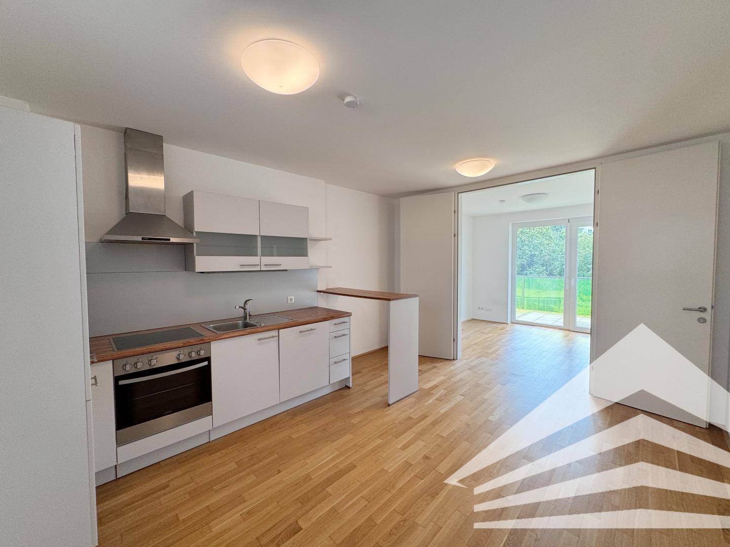 Offene Küche mit modernen Geräten und Zugang zu einem hellen Wohnbereich oder Balkon.
