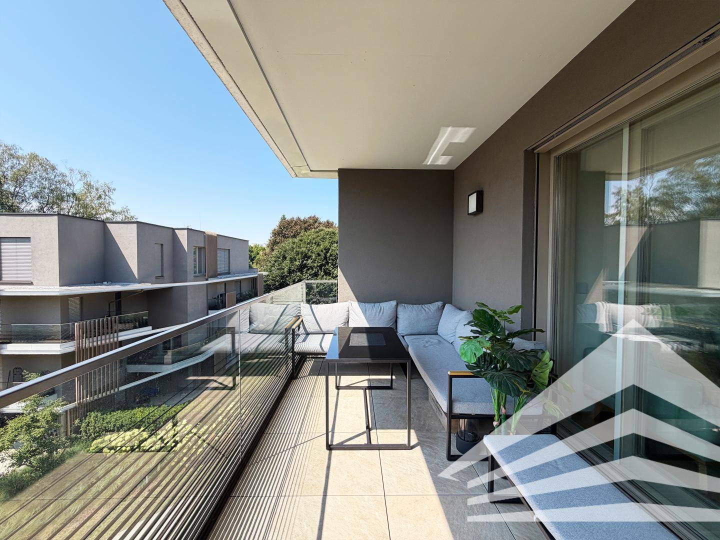 Großer Balkon mit bequemen Lounge-Möbeln und Blick auf die umliegenden Gebäude.
