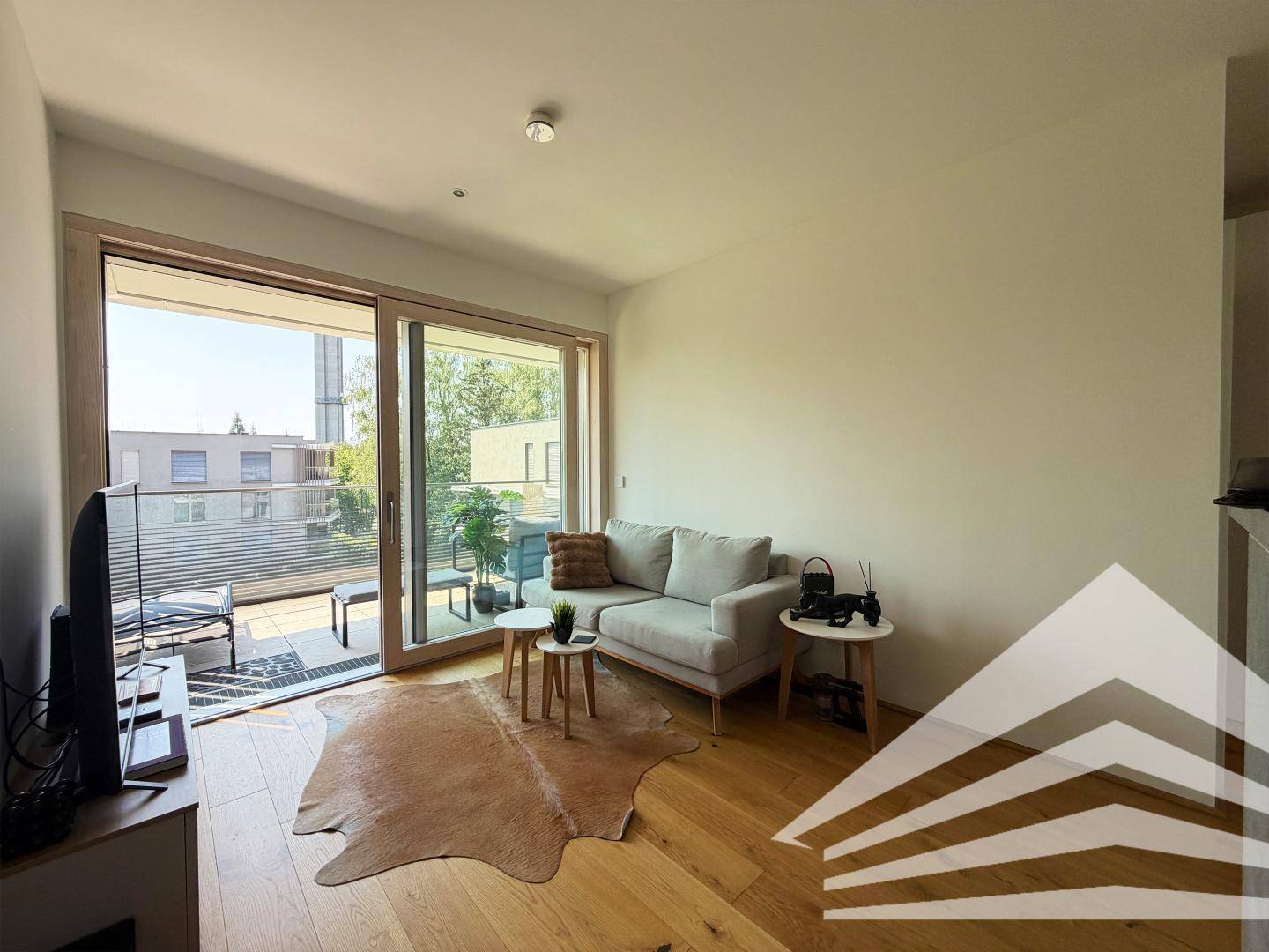 Gemütliches Wohnzimmer mit Holzboden, Sofa und direktem Zugang zur Terrasse.