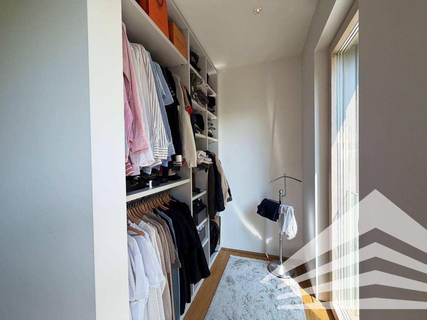 Praktischer begehbarer Kleiderschrank mit viel Stauraum und Tageslicht.