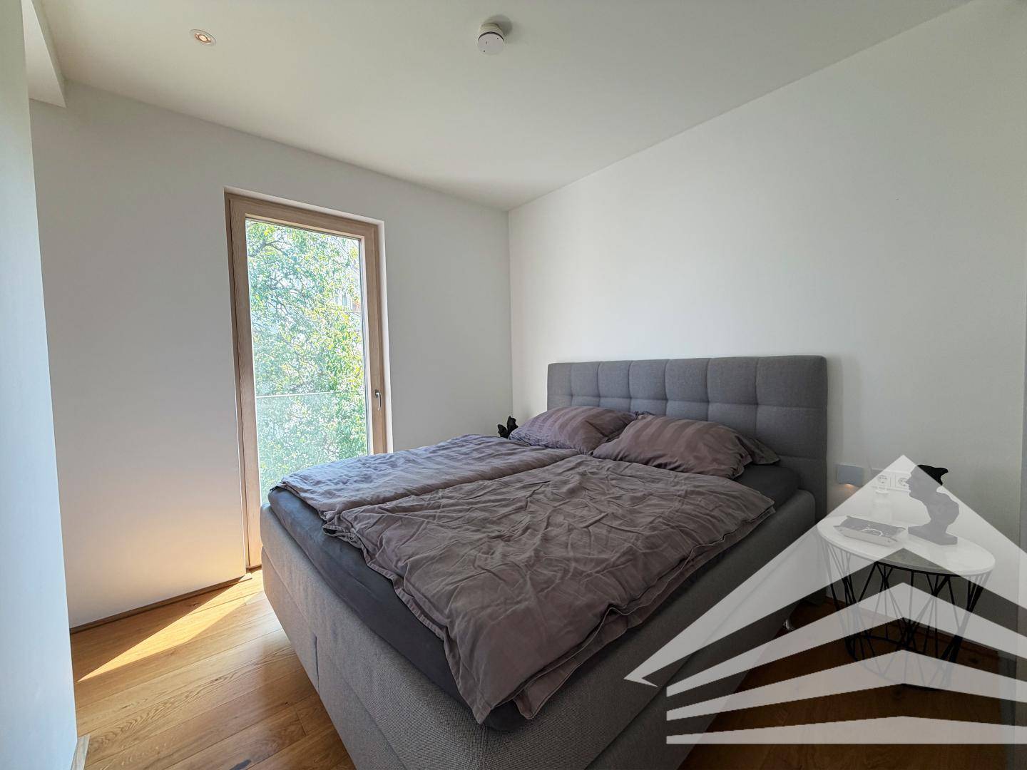 Helles Schlafzimmer mit großem Doppelbett, Holzboden und viel Tageslicht.