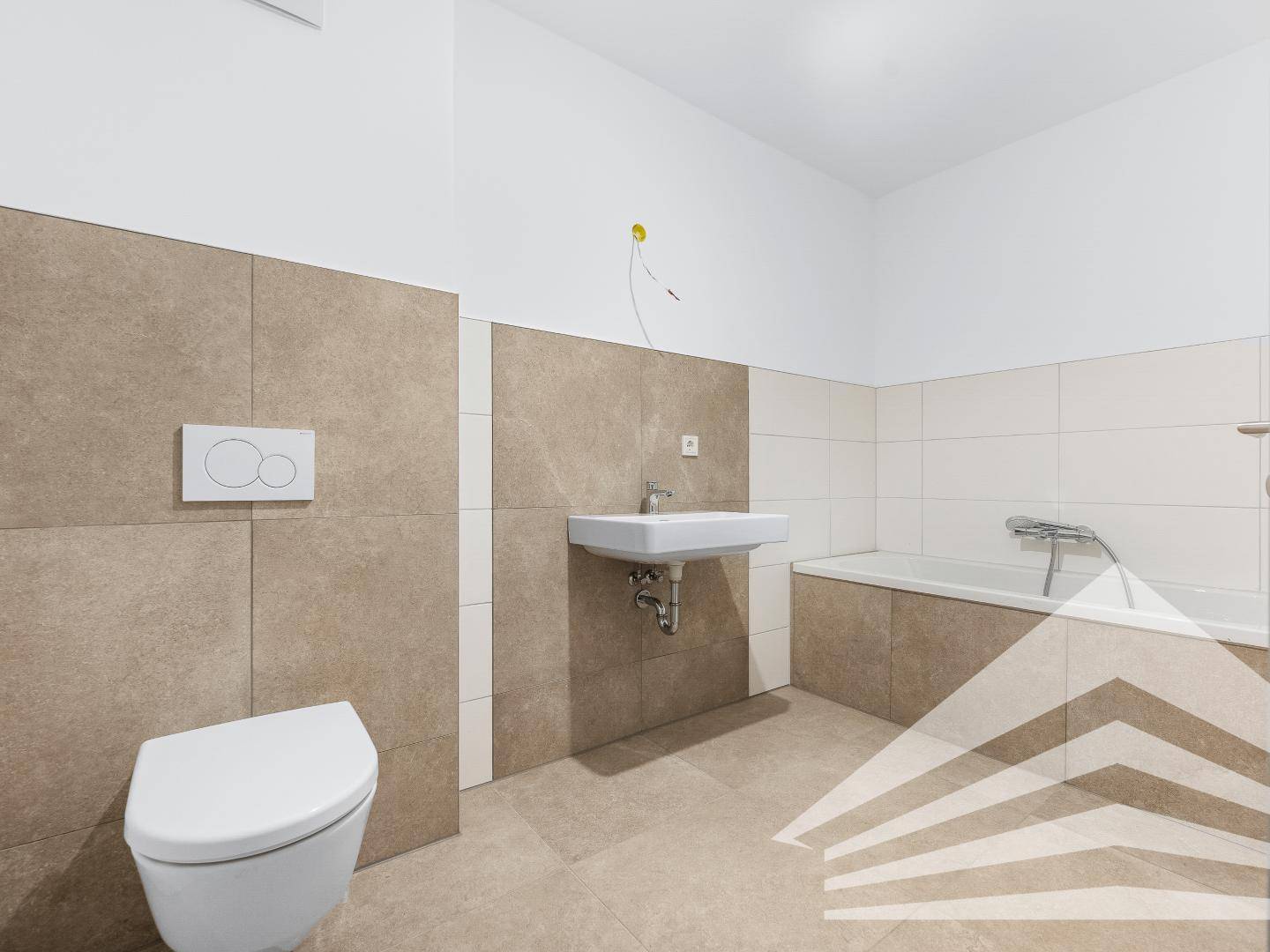 Helles Badezimmer mit Badewanne, Toilette und Waschbecken, ausgestattet mit modernen Fliesen.