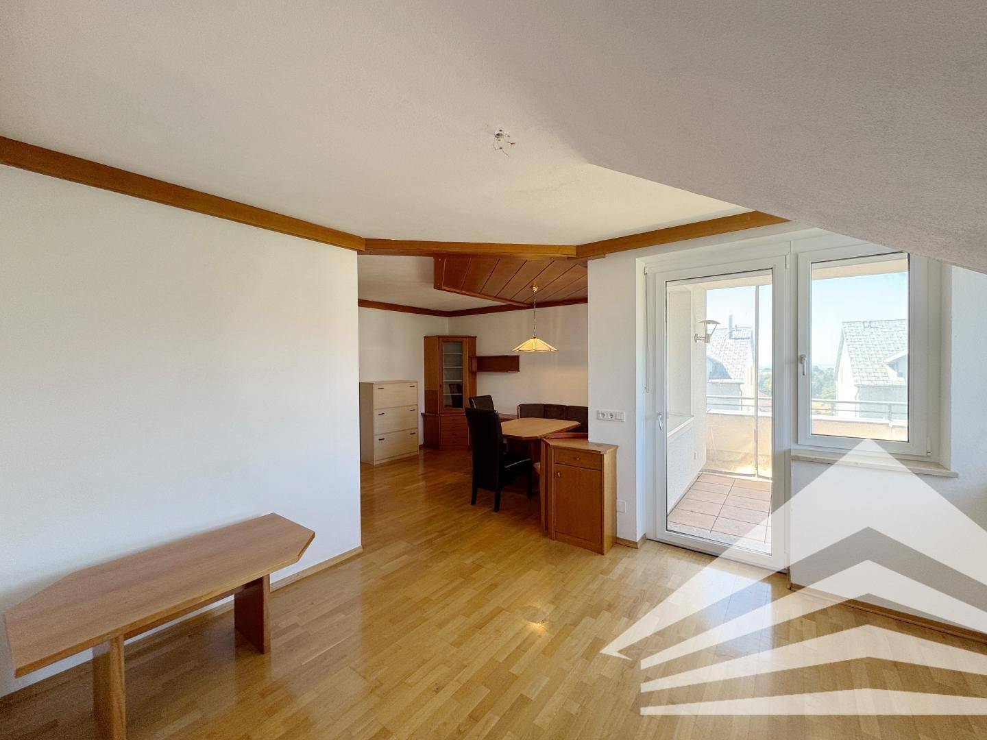 Geräumiger Wohn- und Essbereich mit Holzboden und Zugang zu einem Balkon.