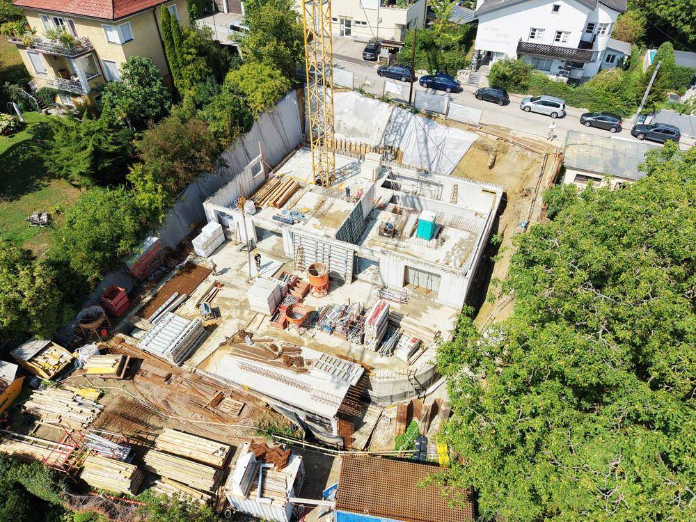 Luftaufnahme einer Baustelle mit Fundamenten und Baukränen für ein neues Wohnprojekt.