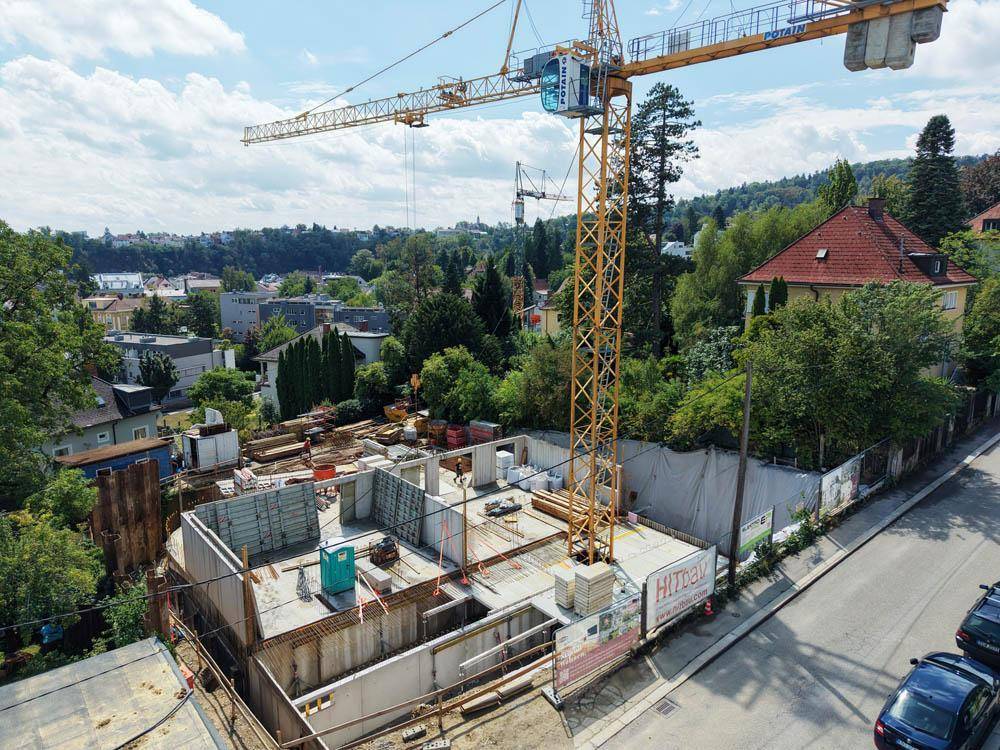 Baustelle aus der Vogelperspektive mit Kran und angrenzender Straße in einer Wohngegend.