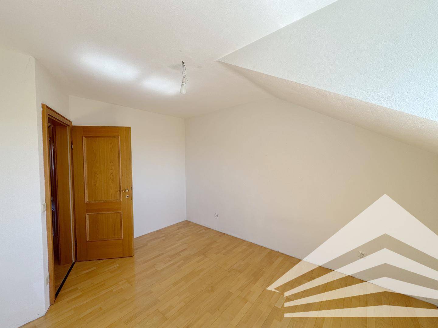 Geräumiges Schlafzimmer mit Holzboden und Holztür.