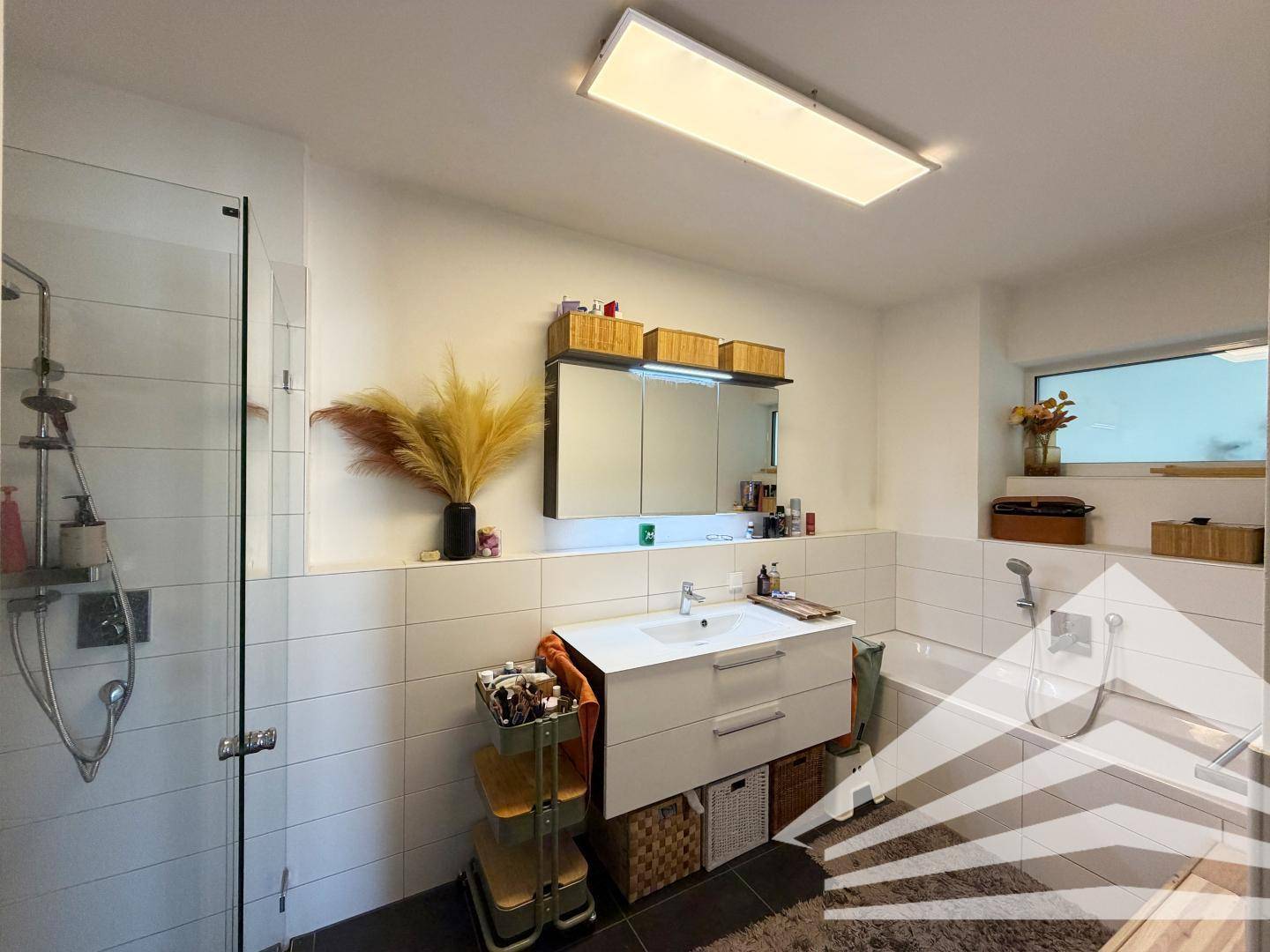 Modernes Badezimmer mit Dusche, Badewanne, Einzelwaschbecken und Fenster.