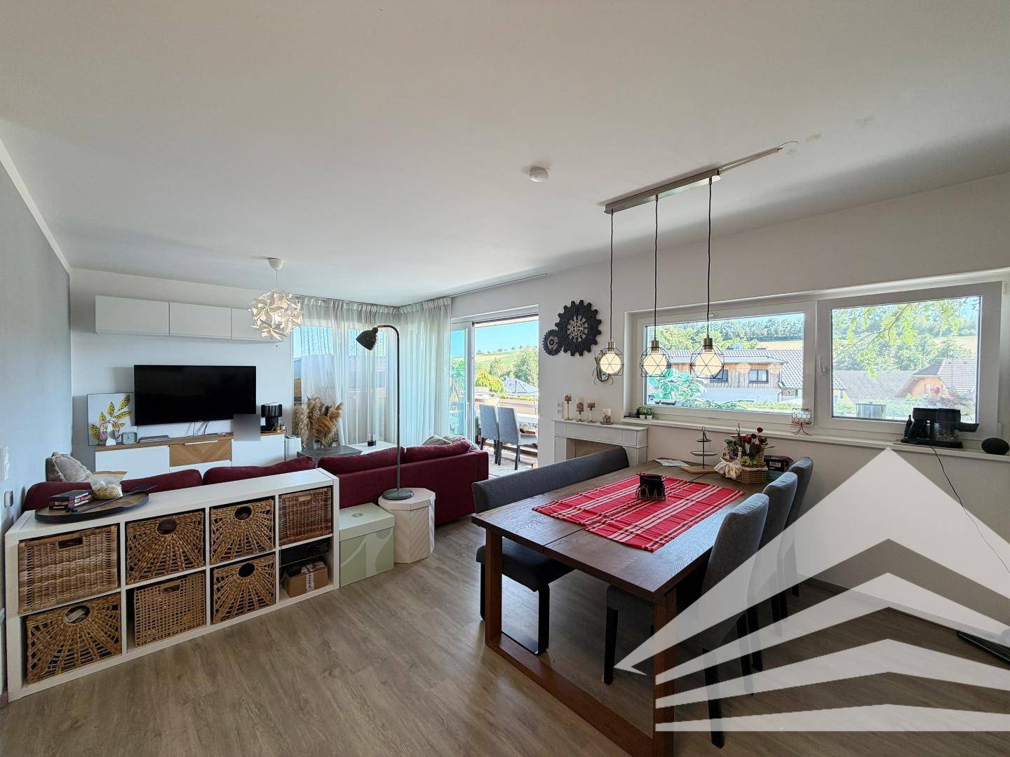 Heller Wohn- und Essbereich mit modernem Laminatboden und Zugang zum Balkon.