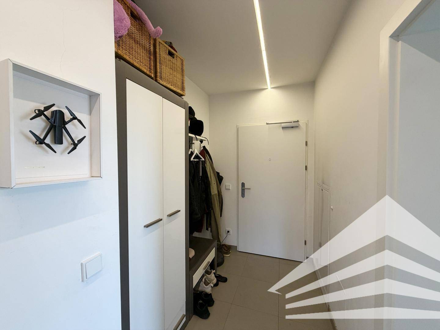 Eingangsbereich mit Garderobe, Schuhschrank und heller Beleuchtung.