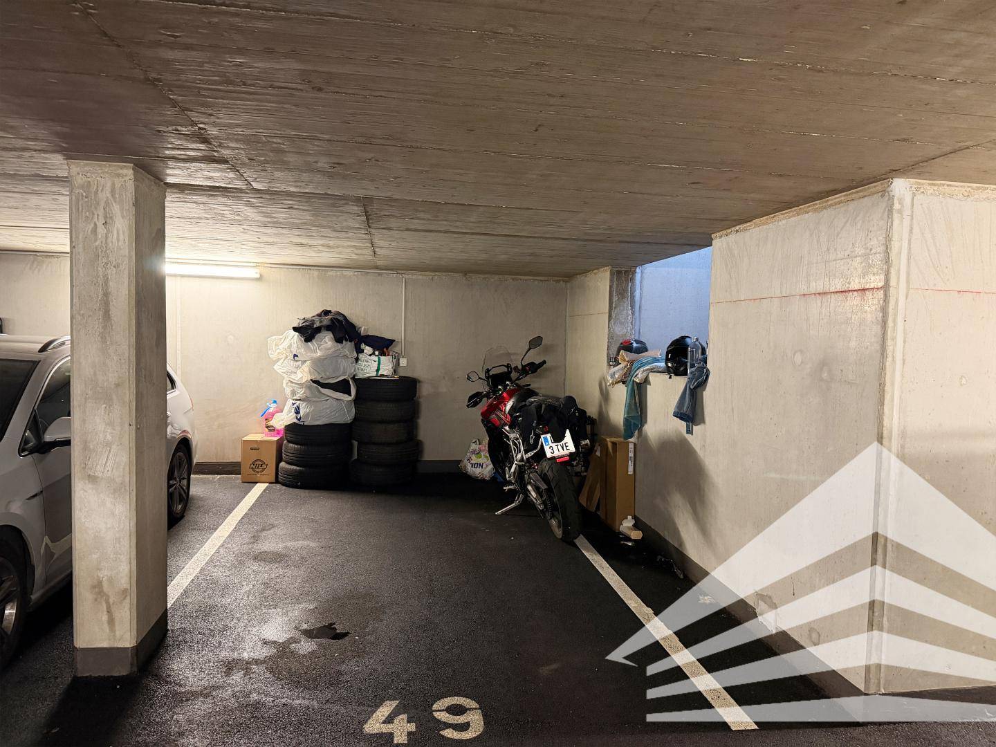 Tiefgaragenstellplatz mit Betonwänden und Platz für ein Fahrzeug und Lagerung.