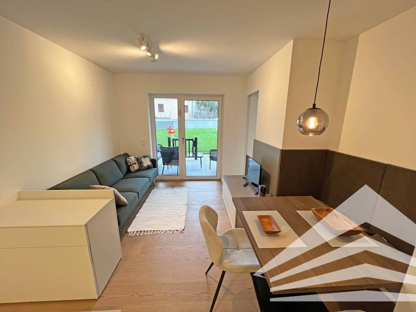 Gemütlicher Wohnbereich mit Sofa, Esstisch und Zugang zur Terrasse durch große Schiebetüren.