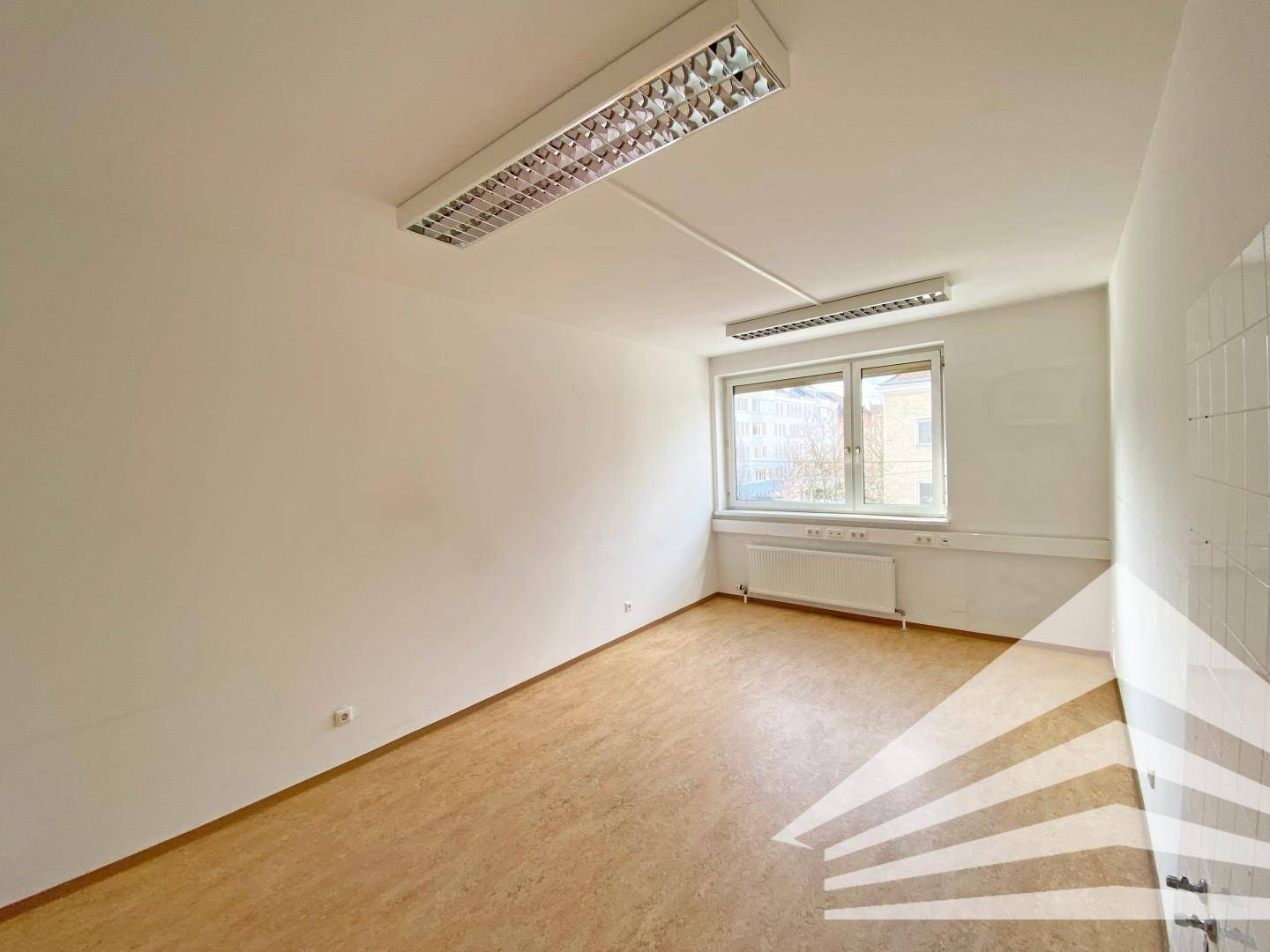 Heller Büroraum mit funktionaler Deckenbeleuchtung und Blick auf die umliegenden Gebäude.