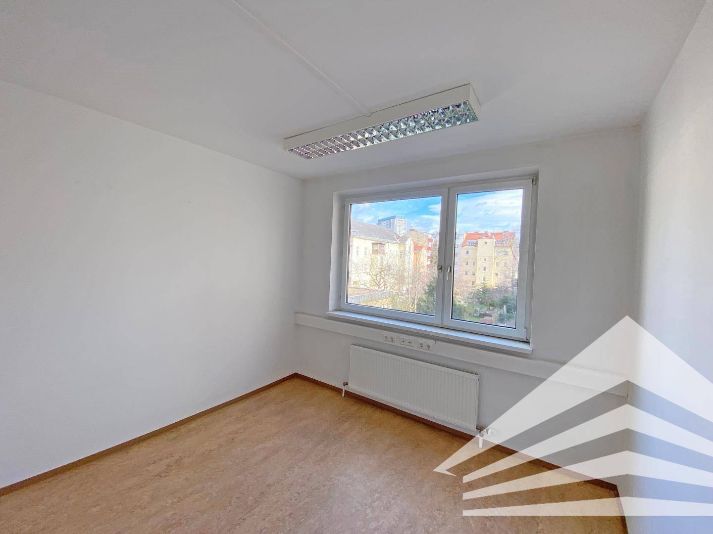 Heller Büroraum mit einem großen Fenster, das eine weite Aussicht auf die Stadt ermöglicht.