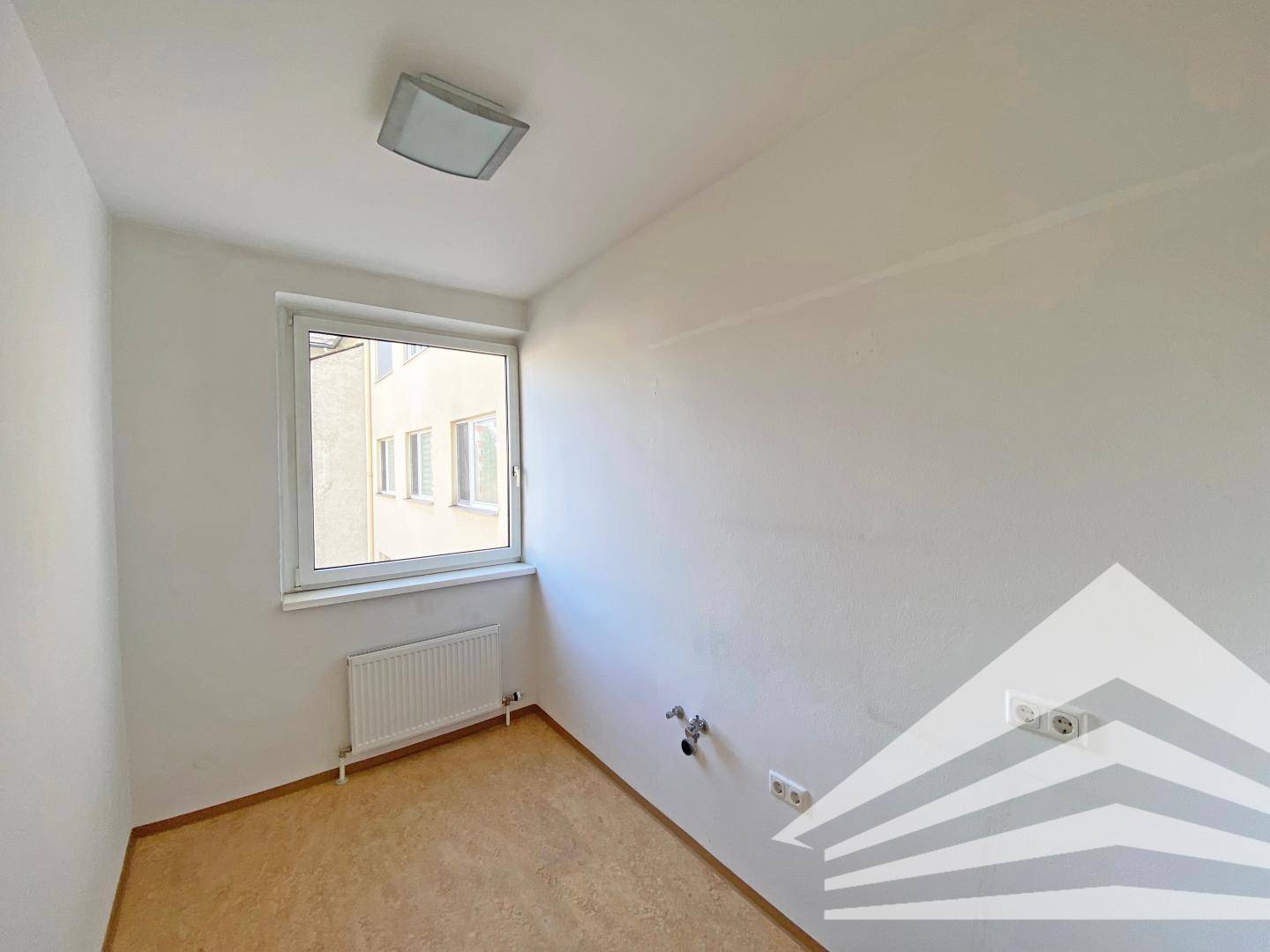 Kleinerer Raum mit einem Fenster, das Tageslicht spendet, und einfacher Deckenbeleuchtung.
