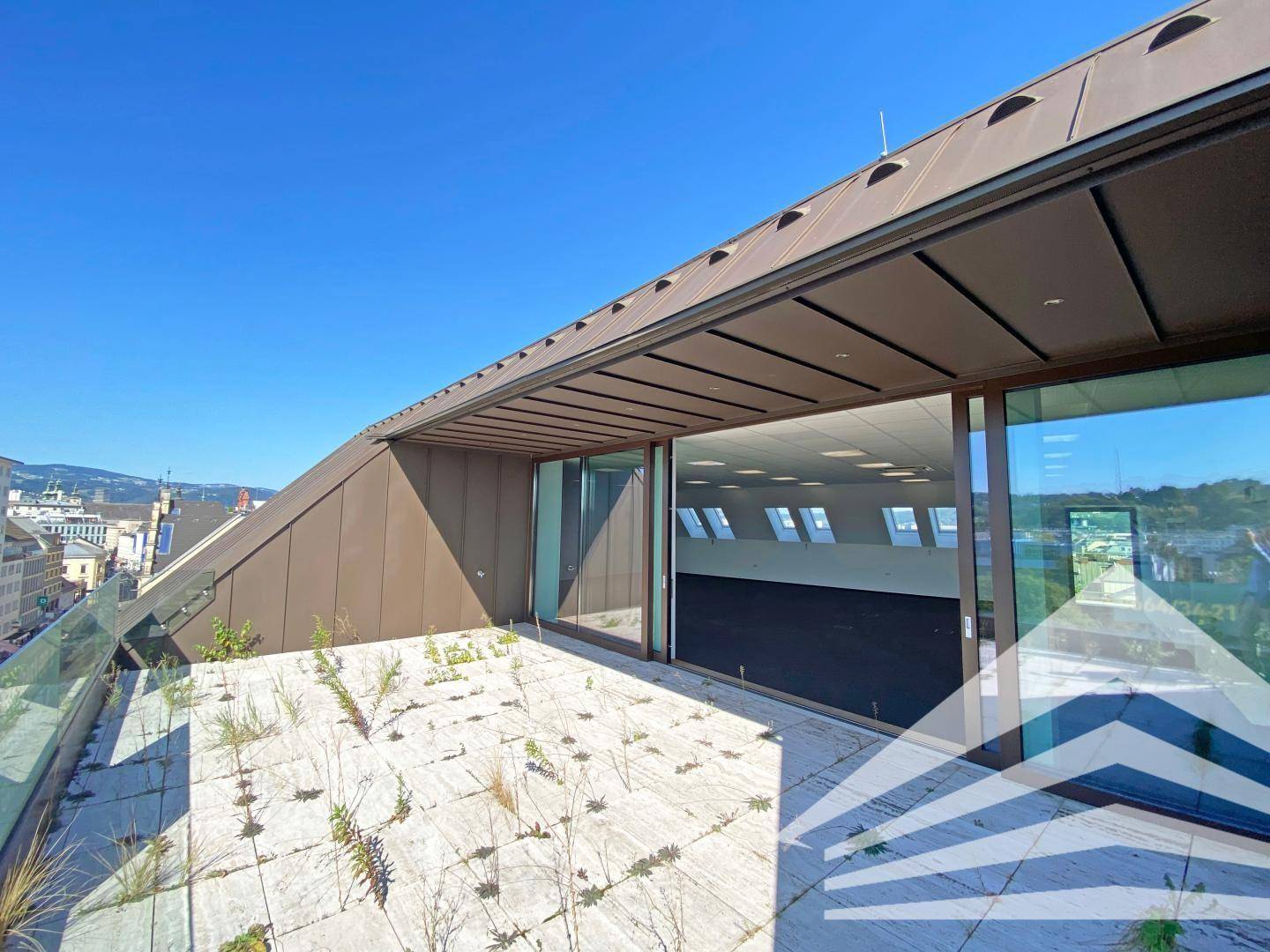 Weitläufige Dachterrasse mit Steinplatten und Blick auf die umliegende Stadtlandschaft.