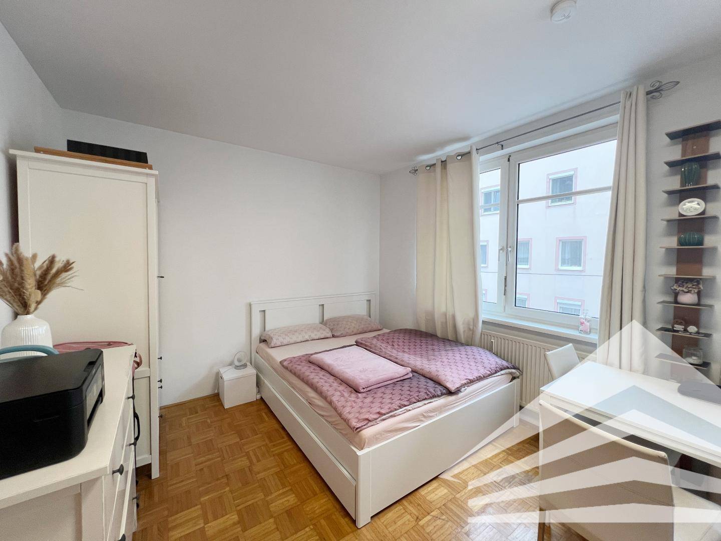 Gemütliches Schlafzimmer mit Doppelbett, Nachttischen und einem Schreibtisch am Fenster.