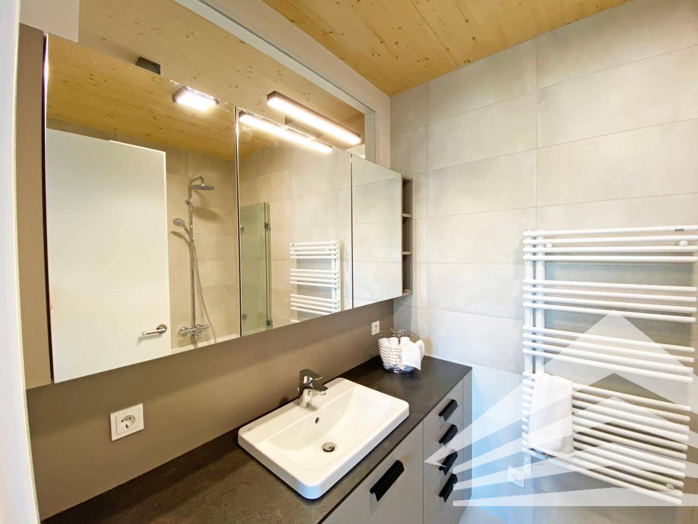 Modernes Badezimmer mit Waschtisch, Spiegel und beheiztem Handtuchhalter.