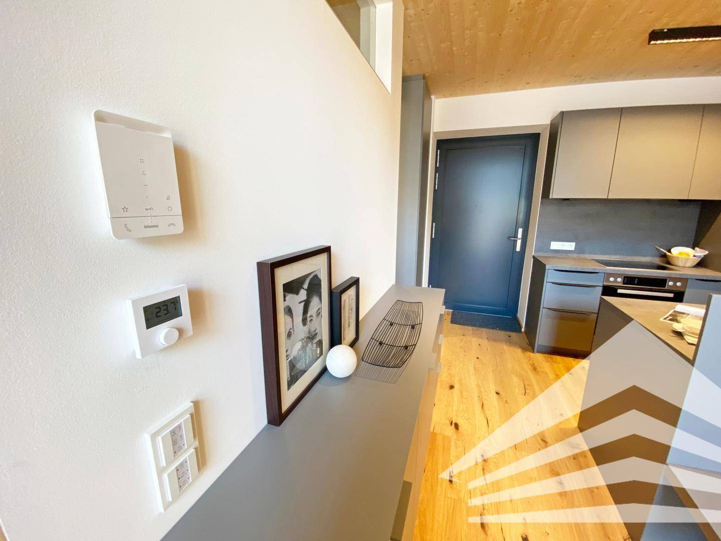 Küchenbereich mit moderner Ausstattung, Holzboden und Smart-Home-Steuerung an der Wand.