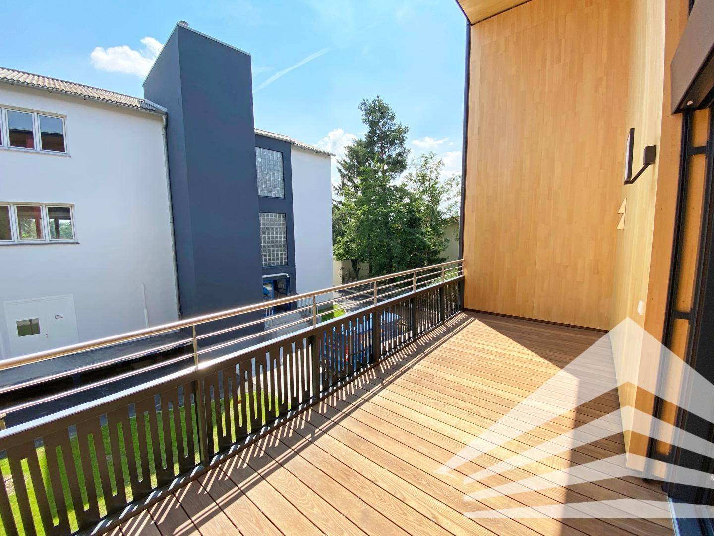 Großer Holzbalkon mit Metallgeländer und Blick auf die umliegenden Gebäude.