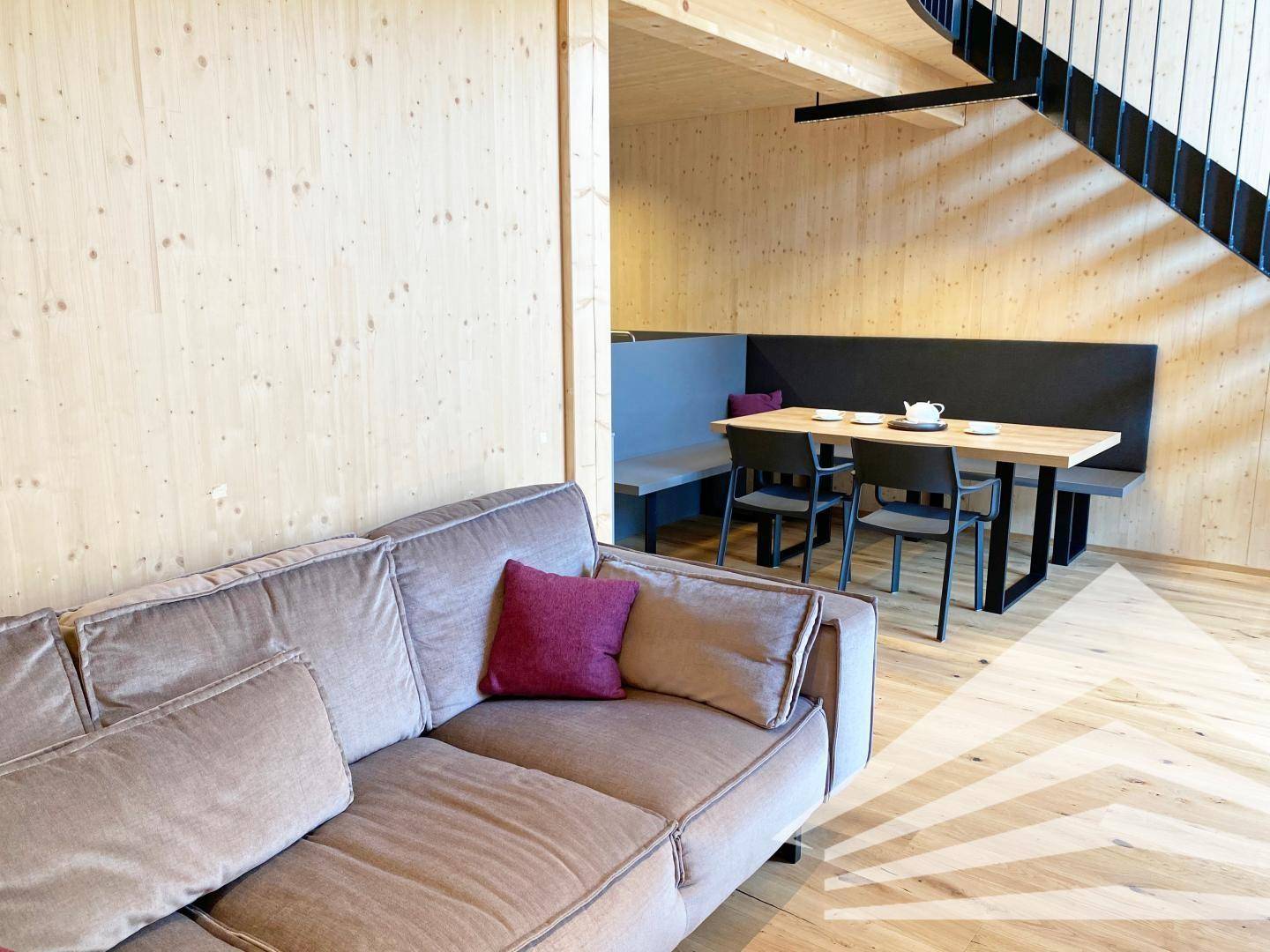 Gemütlicher Essbereich mit Holztisch und Sitzbank, angrenzend an eine moderne Couch.