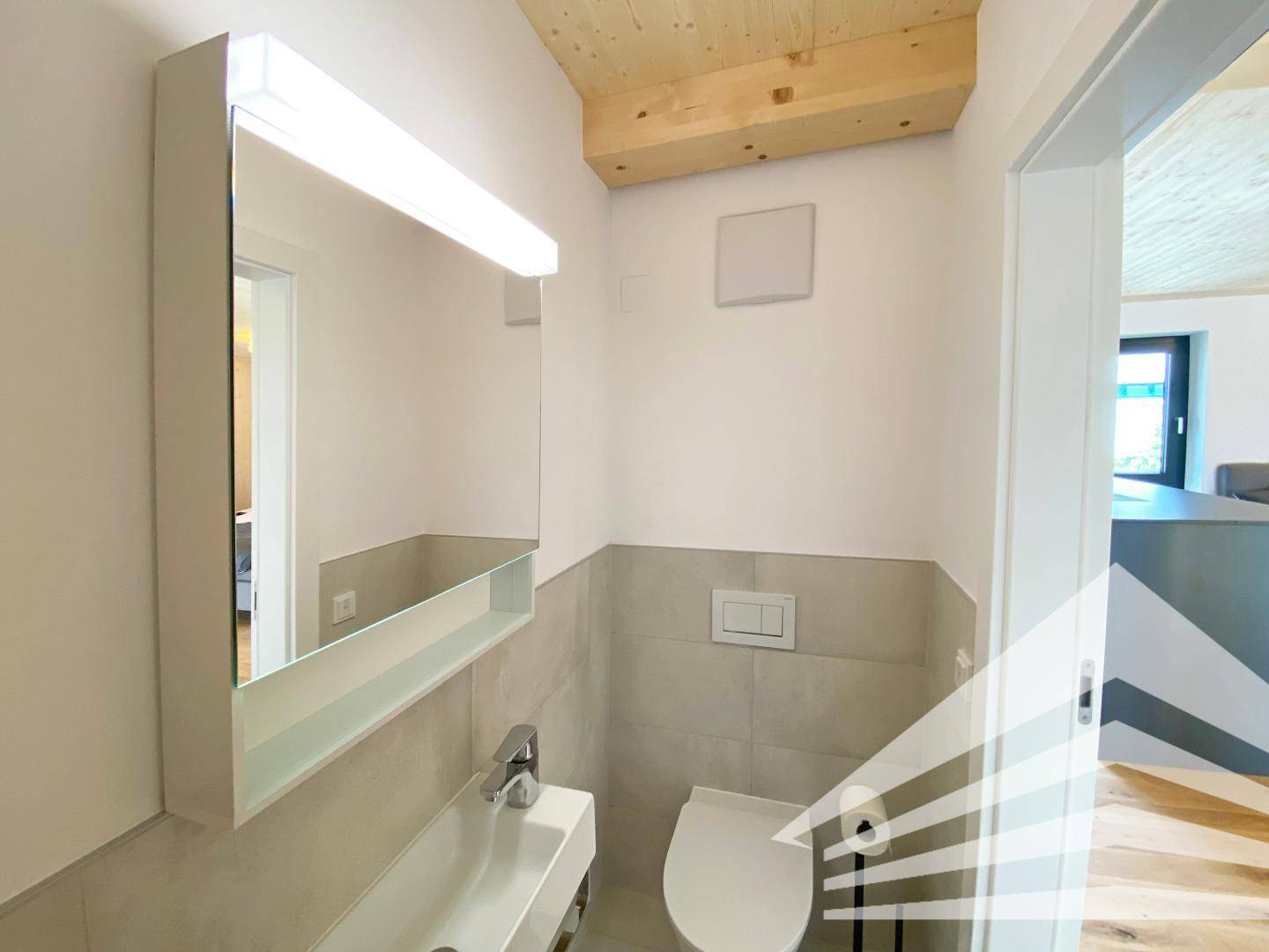 Helles Gäste-WC mit wandhängender Toilette, kleinem Waschbecken und Spiegelschrank.