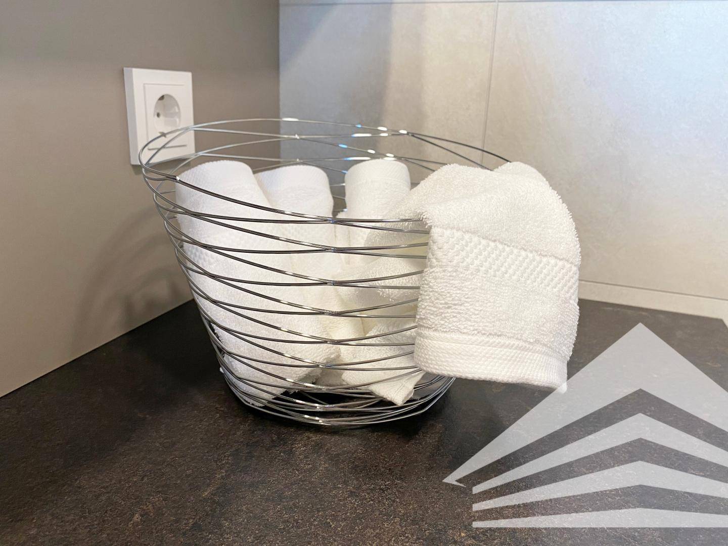 Dekorative Handtücher in einem Drahtkorb auf der Ablage im modernen Badezimmer.