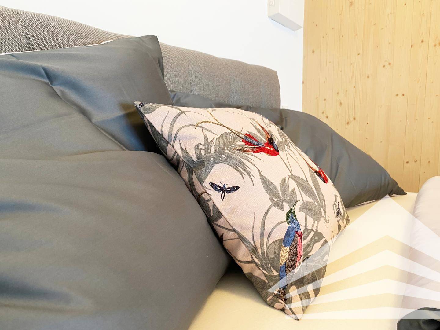 Gemütliches Schlafzimmer mit modernen Kissen und Holzwänden, die eine warme Atmosphäre schaffen.