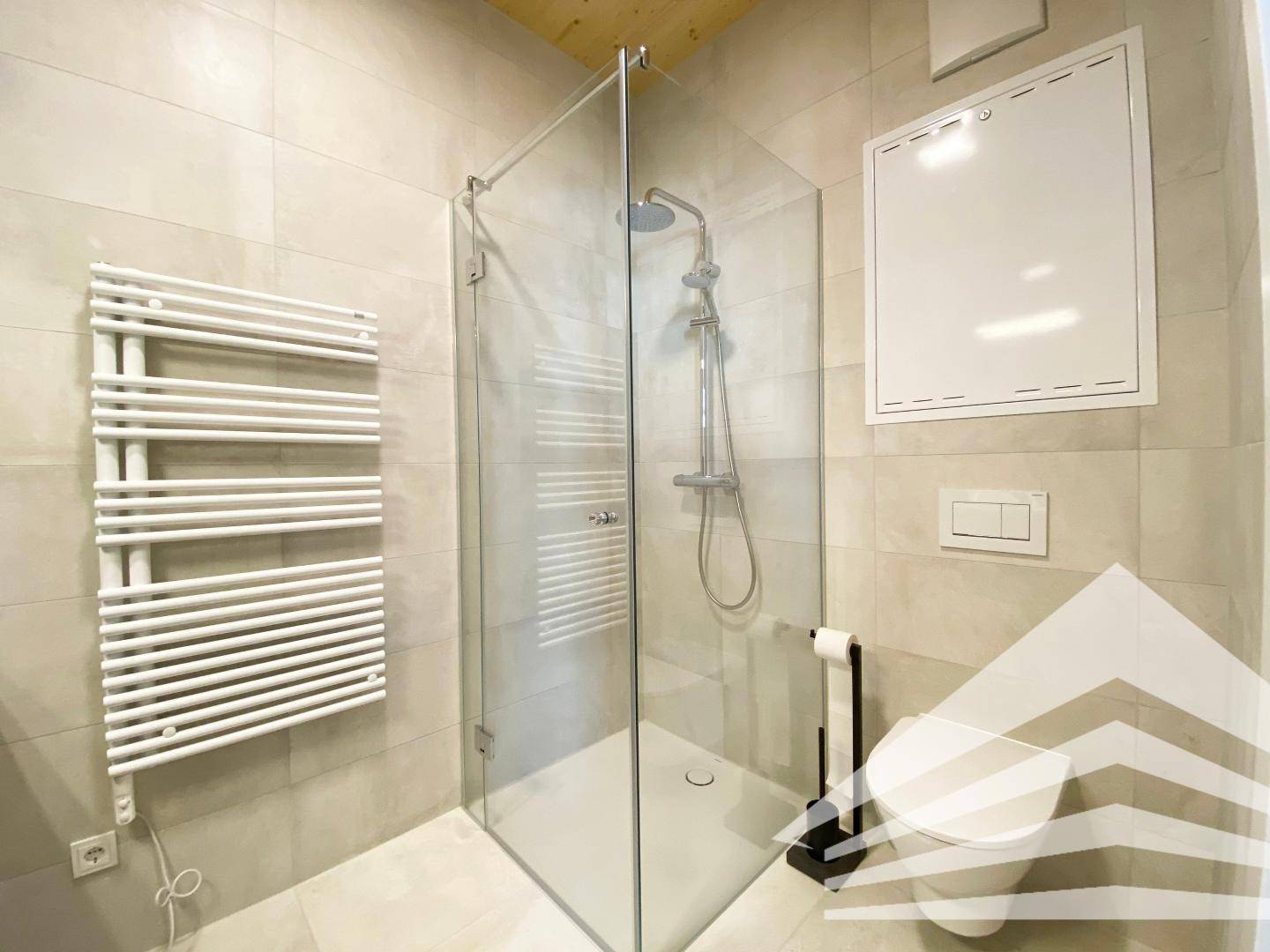 Begehbare Dusche mit Glaswand, beheiztem Handtuchhalter und wandhängendem WC.