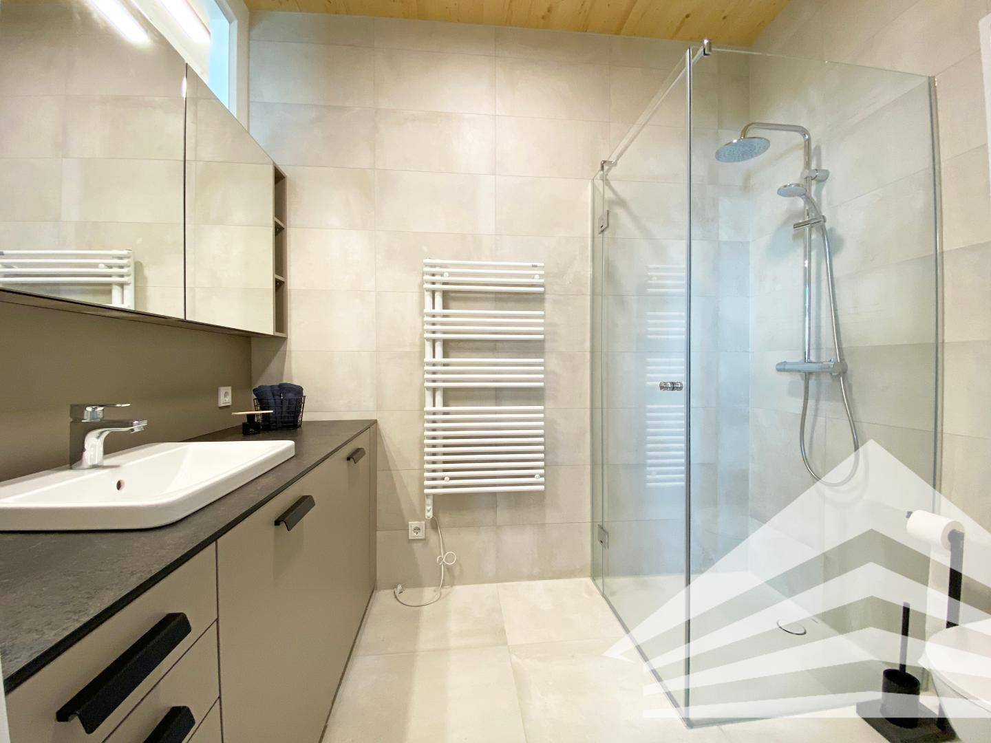 Modernes Badezimmer mit begehbarer Dusche, Einzelwaschbecken und beheiztem Handtuchhalter.