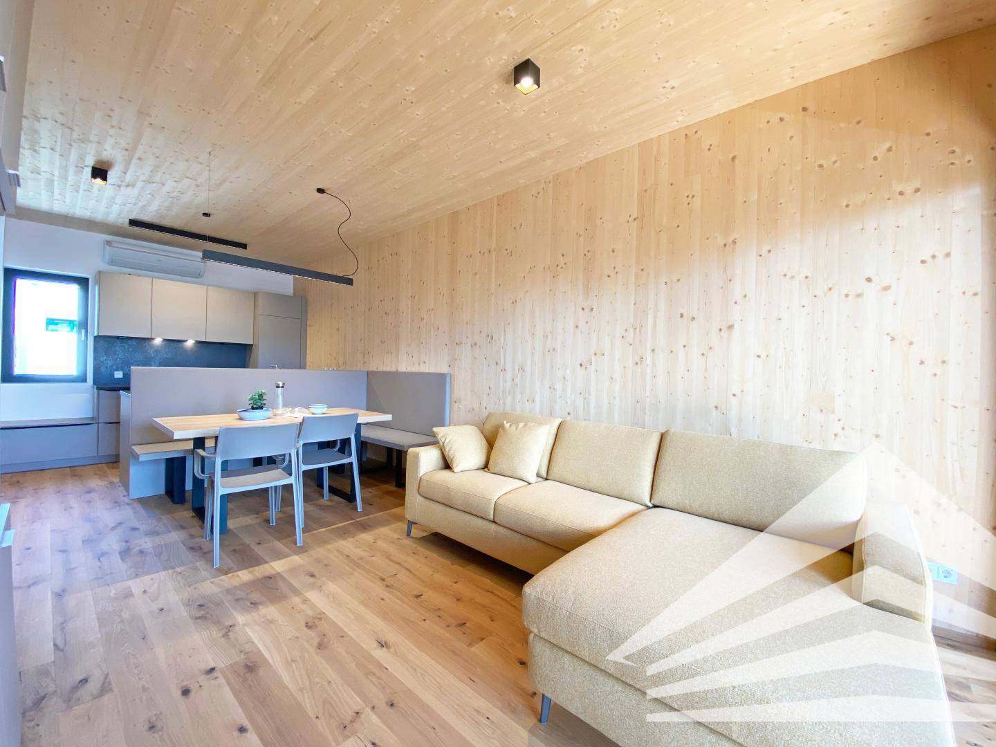 Geräumiger offener Wohnbereich mit beigem Sofa, Holzwänden und Essbereich.