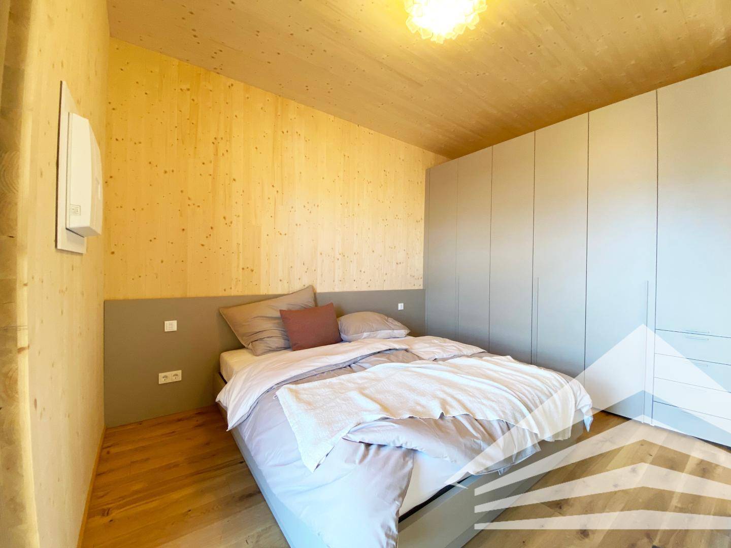 Schlafzimmer mit Doppelbett, Einbauschrank und Holzwänden sowie Holzdecke.