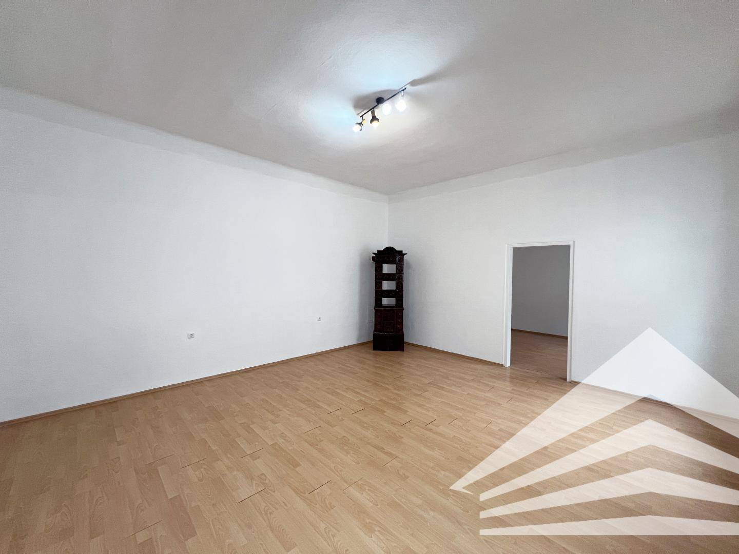 Geräumiges Zimmer mit hellem Parkettboden und einem traditionellen Holzschrank.