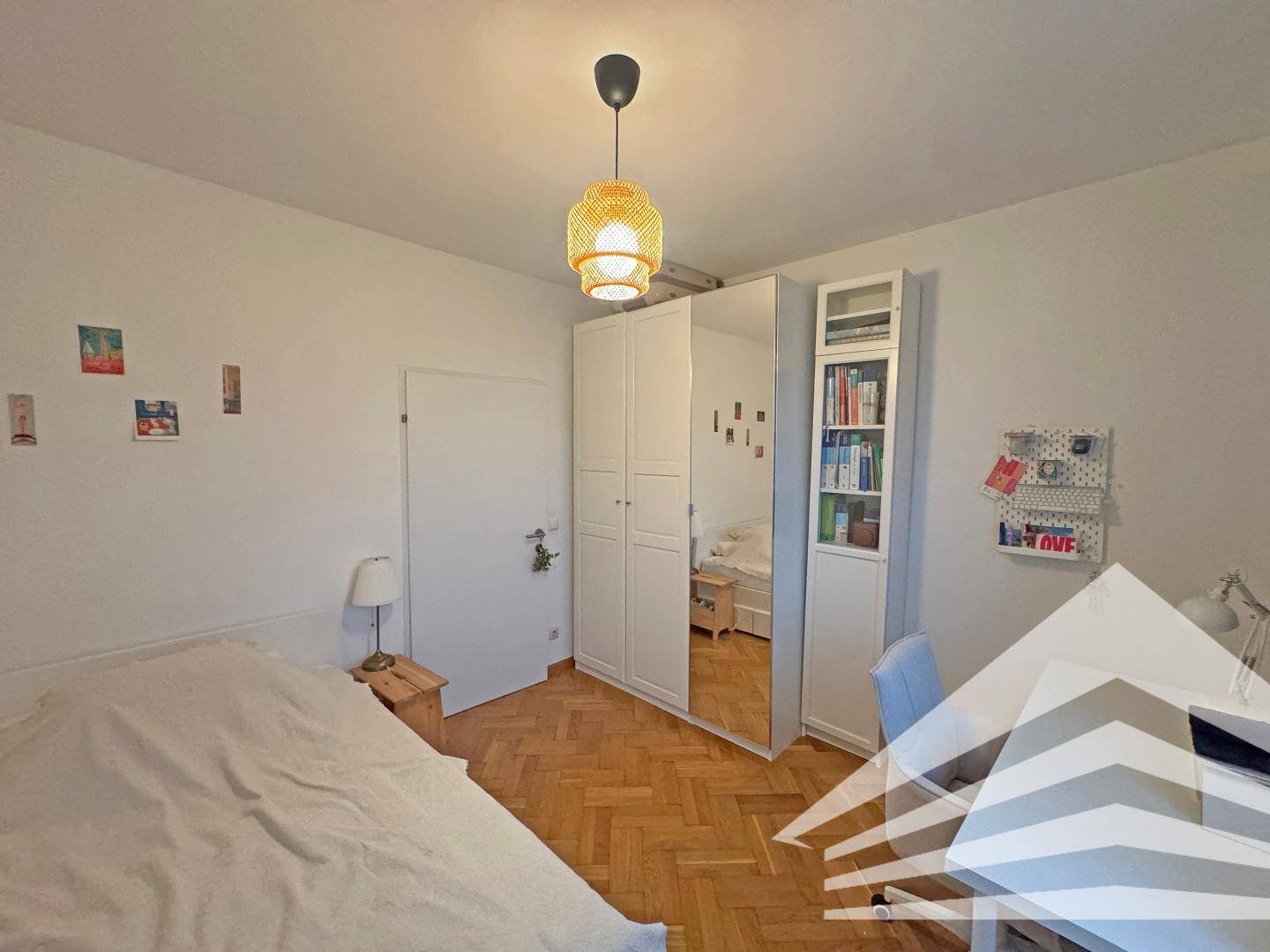 Schlafzimmer mit Parkettboden, großem Kleiderschrank und modernem Hängeregal.