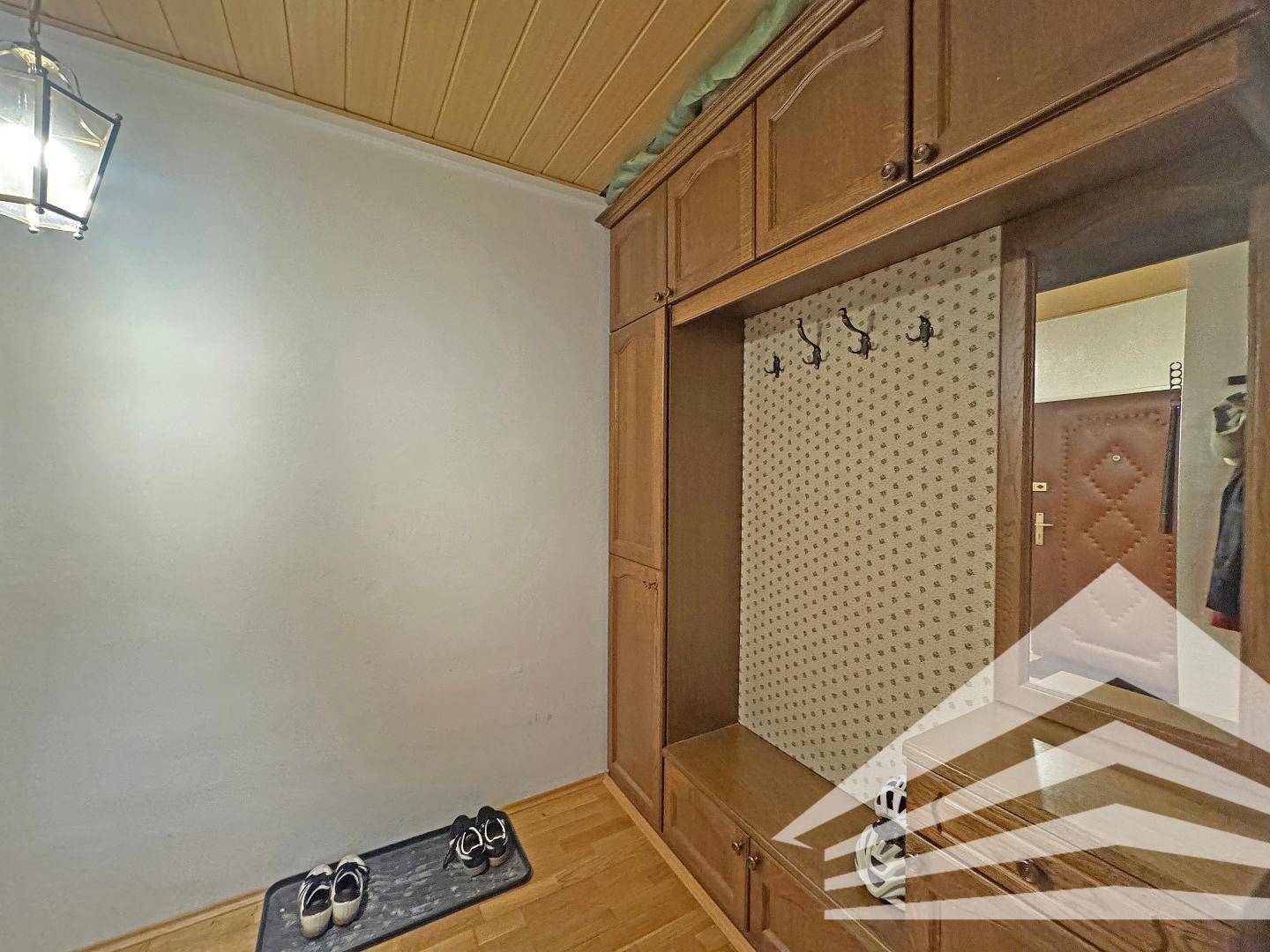 Eingangsbereich mit Holzvertäfelung an der Decke und praktischer Garderobe mit Spiegel.