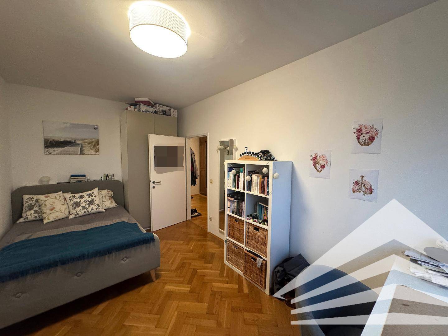 Gemütliches Schlafzimmer mit Parkettboden, Einzelbett und praktischem Bücherregal.