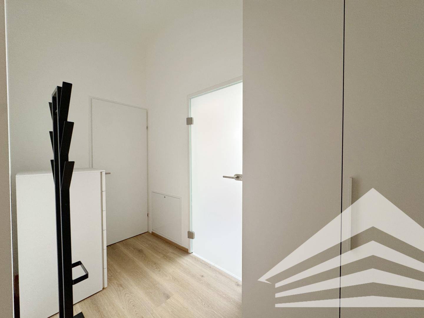Heller Flur mit modernem Laminatboden, Garderobe und Türen zu weiteren Räumen.