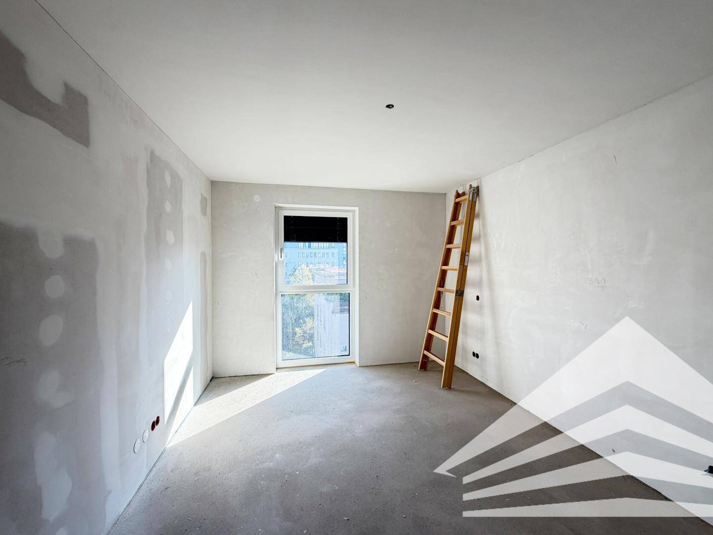 Unfertiges Zimmer mit einem Fenster und einer Leiter, bereit für den Innenausbau.