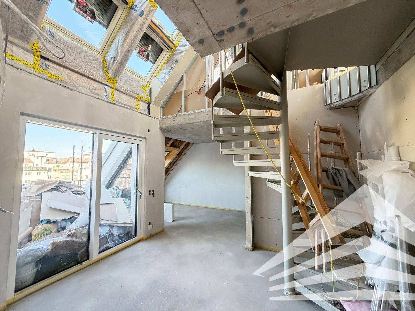 Unfertiger Raum mit Wendeltreppe, Dachfenstern und Baumaterialien.