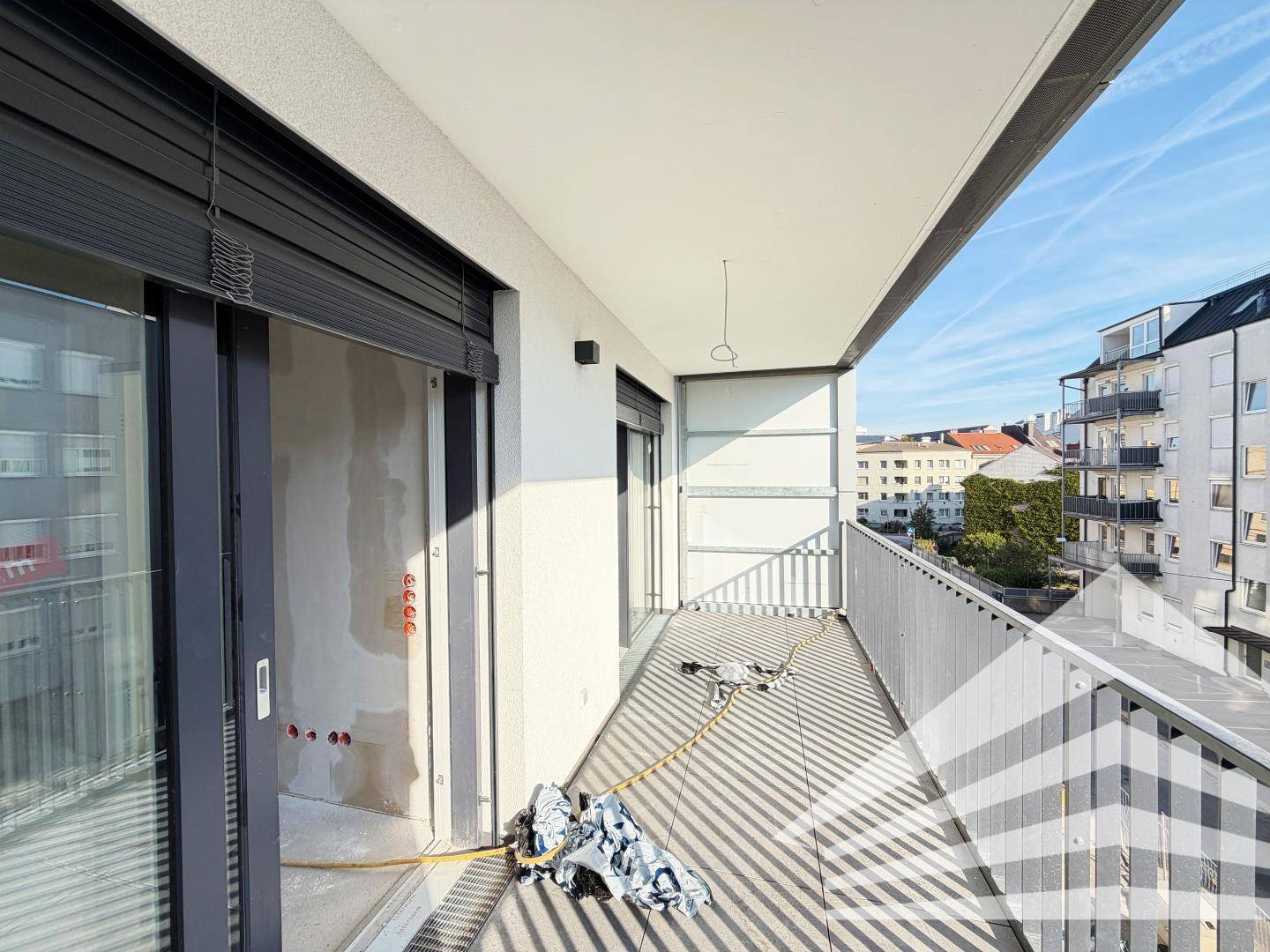 Unfertiger Balkon einer Wohnung mit Geländer und Blick auf umliegende Gebäude.