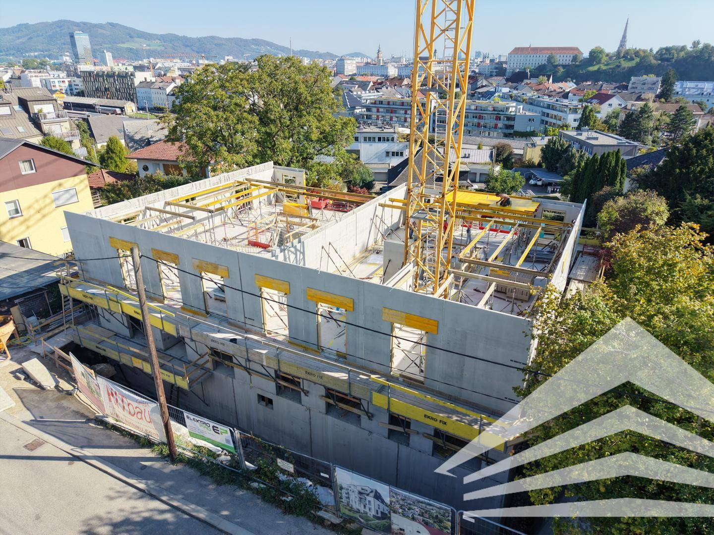 Detailansicht der Baustelle mit Rohbau und Gerüst, umgeben von städtischer Bebauung.