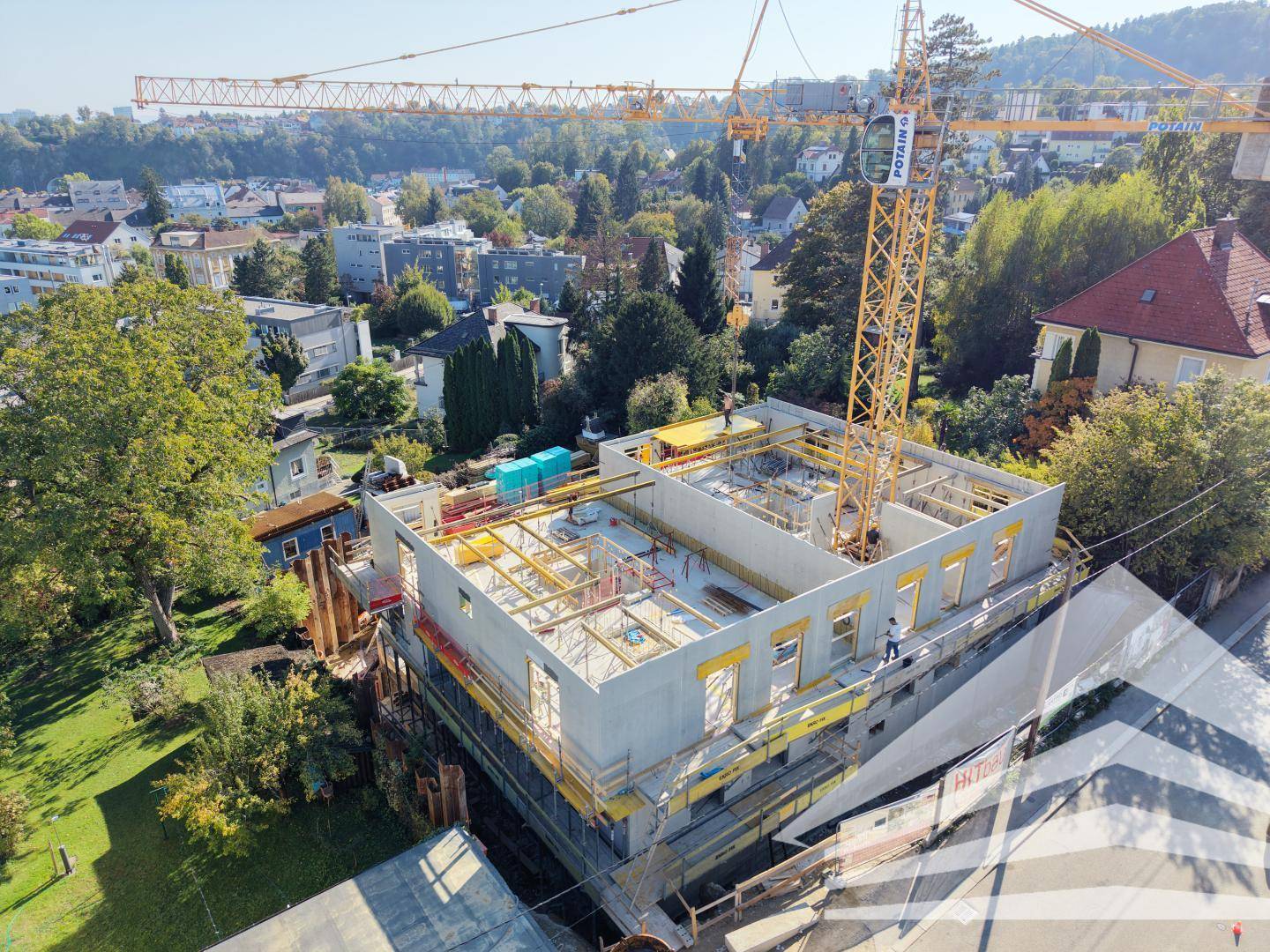 Luftaufnahme der Baustelle mit Kran und im Bau befindlichem Gebäude in städtischer Umgebung.