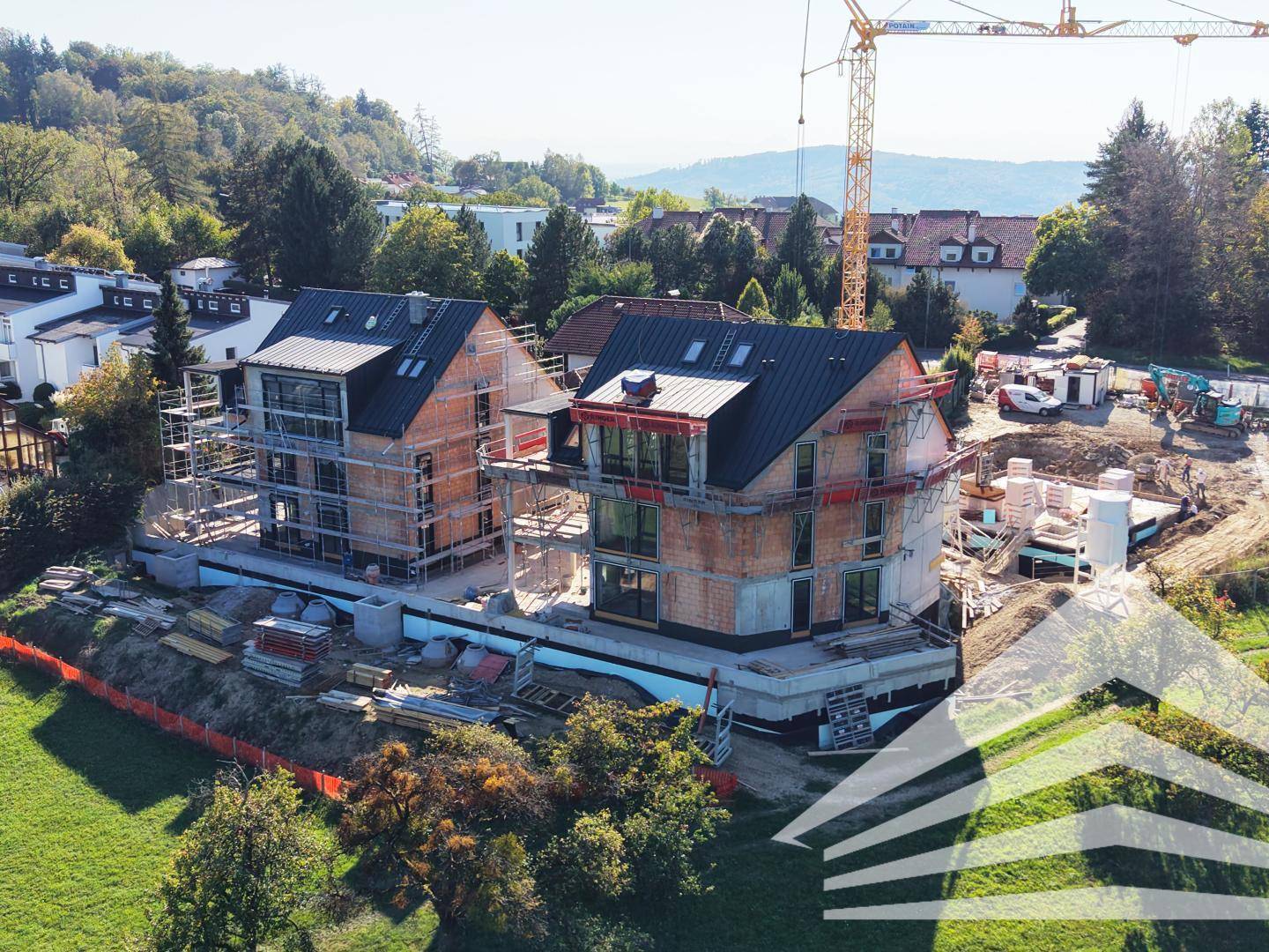 Überblick über die Baustelle mit zwei im Bau befindlichen Mehrfamilienhäusern und Kran.